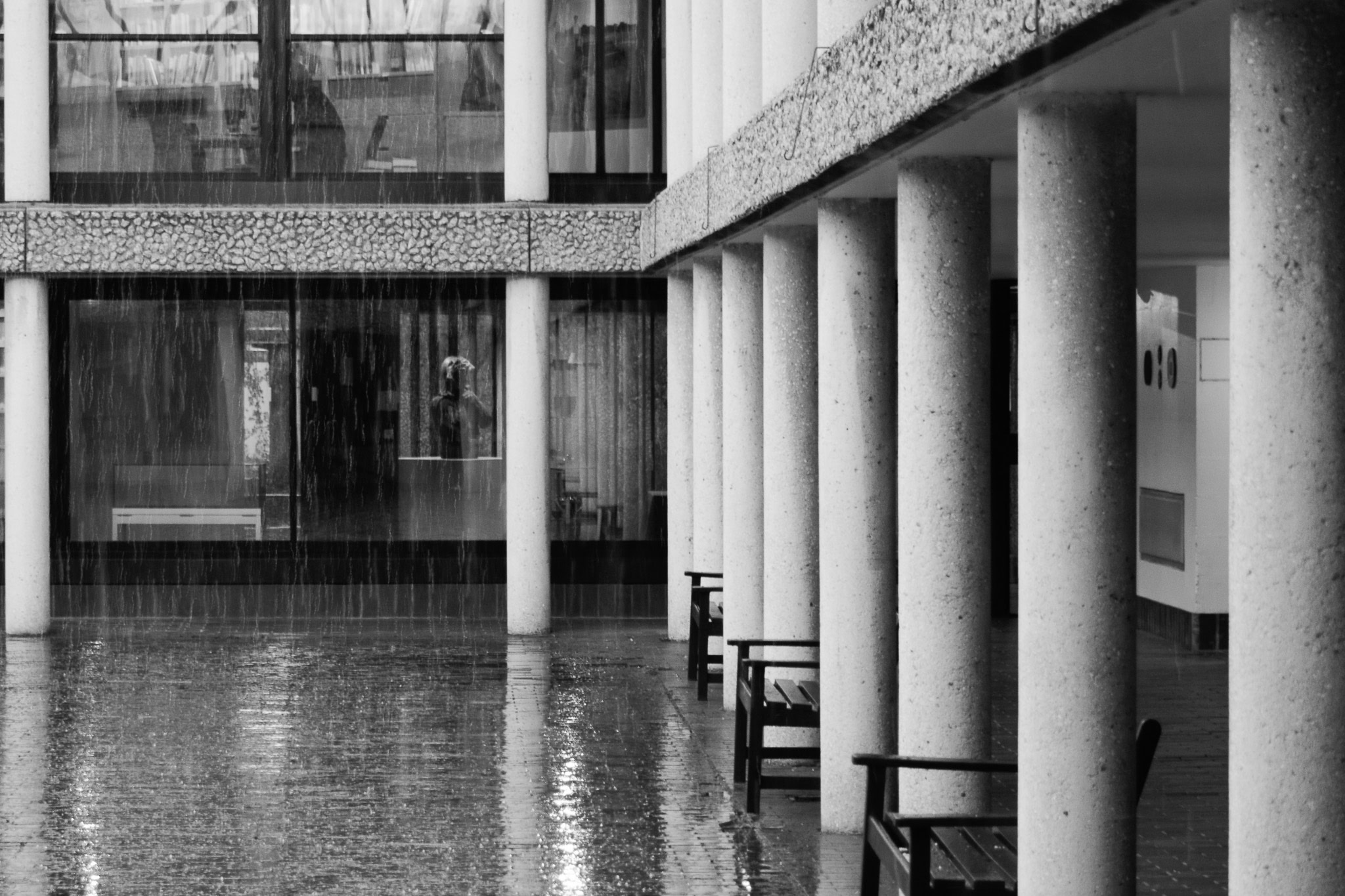 A black and white photo of Berlin Quad on a rainy day, showing the cloisters supported by white columns.