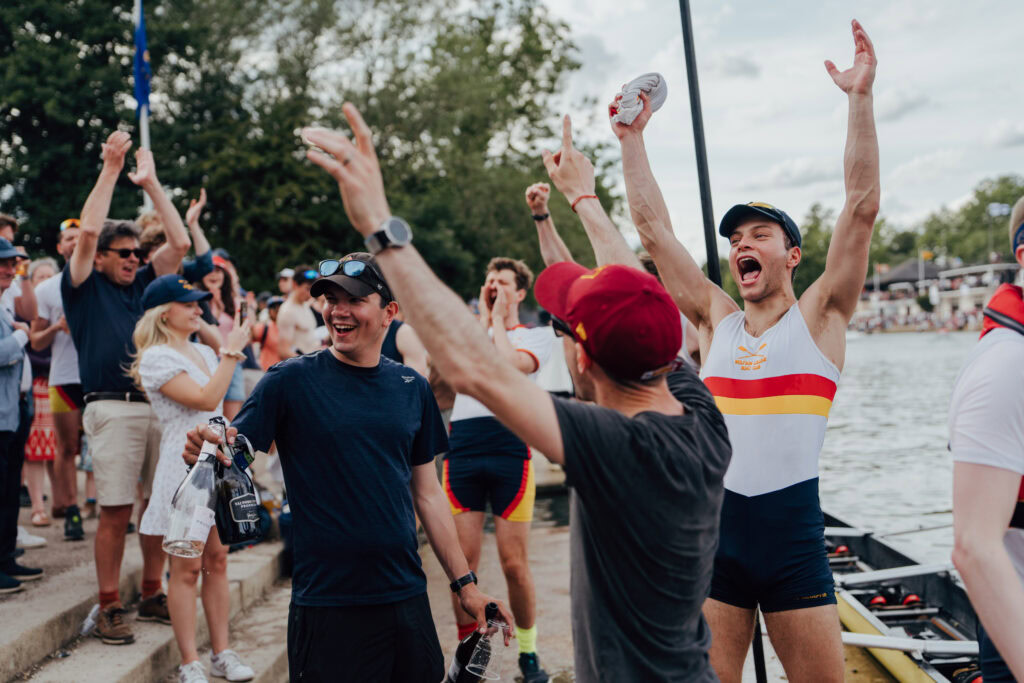 Wolfson College rowers and supporters cheer ecstatically by the riverside after winning Head of the River at Summer Eights.